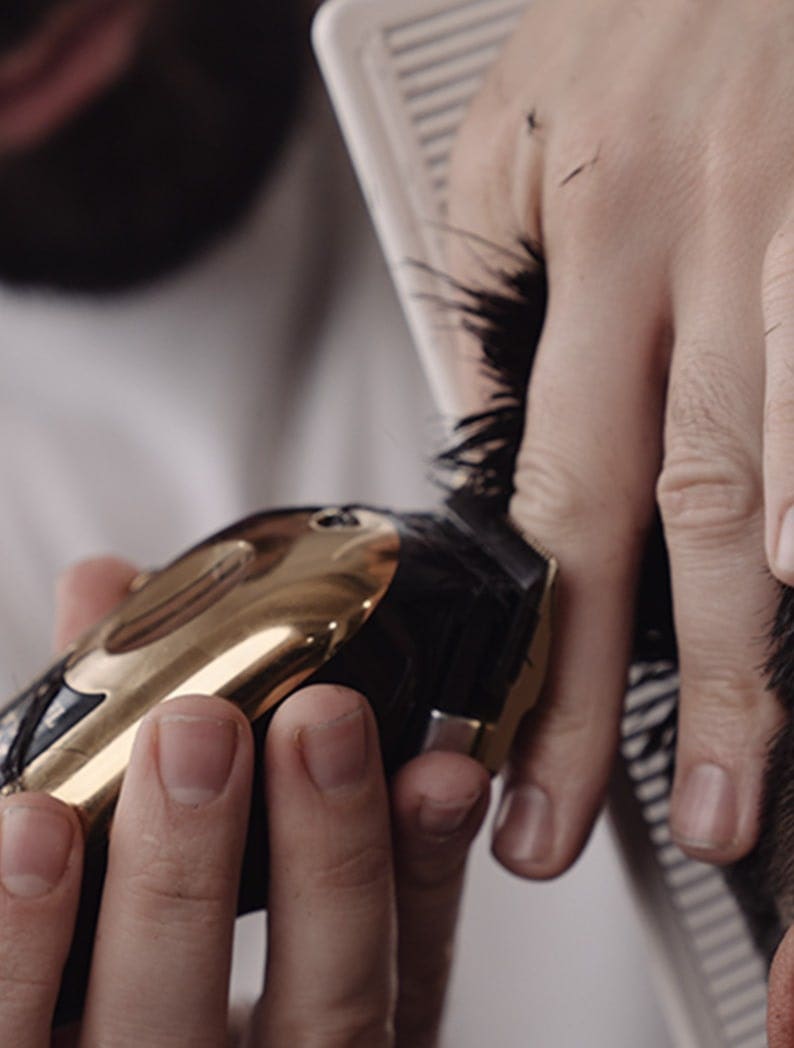 Barber using a Wahl 5 Star Gold Cordless Magic Clip to cut model's hair.