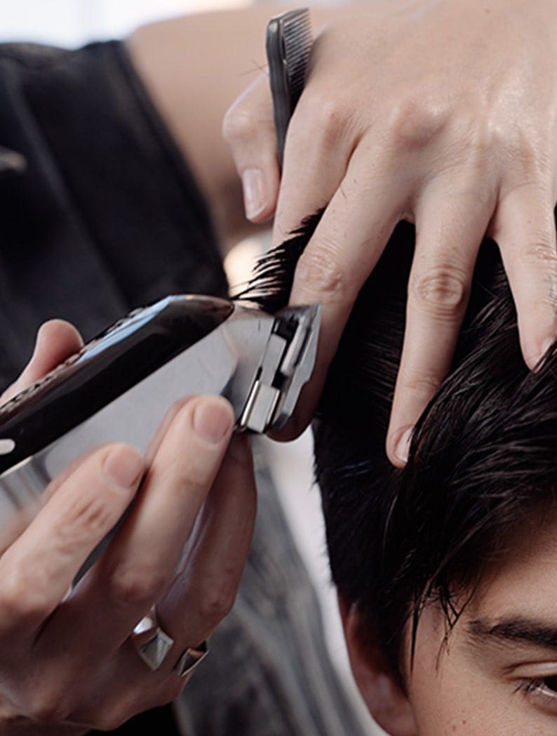 Barber holding model's hair and clipping it using a Wahl Cord/Cordless Senior clipper.