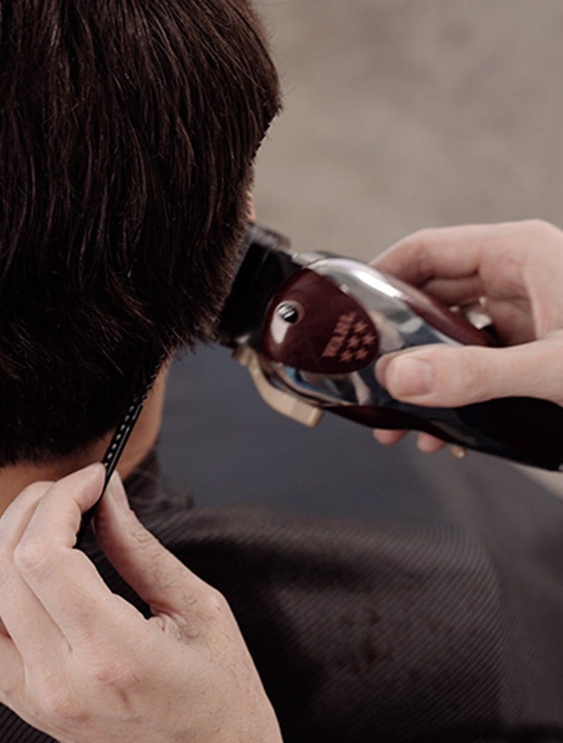 Barber cutting the back of a model's hair using a Wahl Magic Clip clipper.